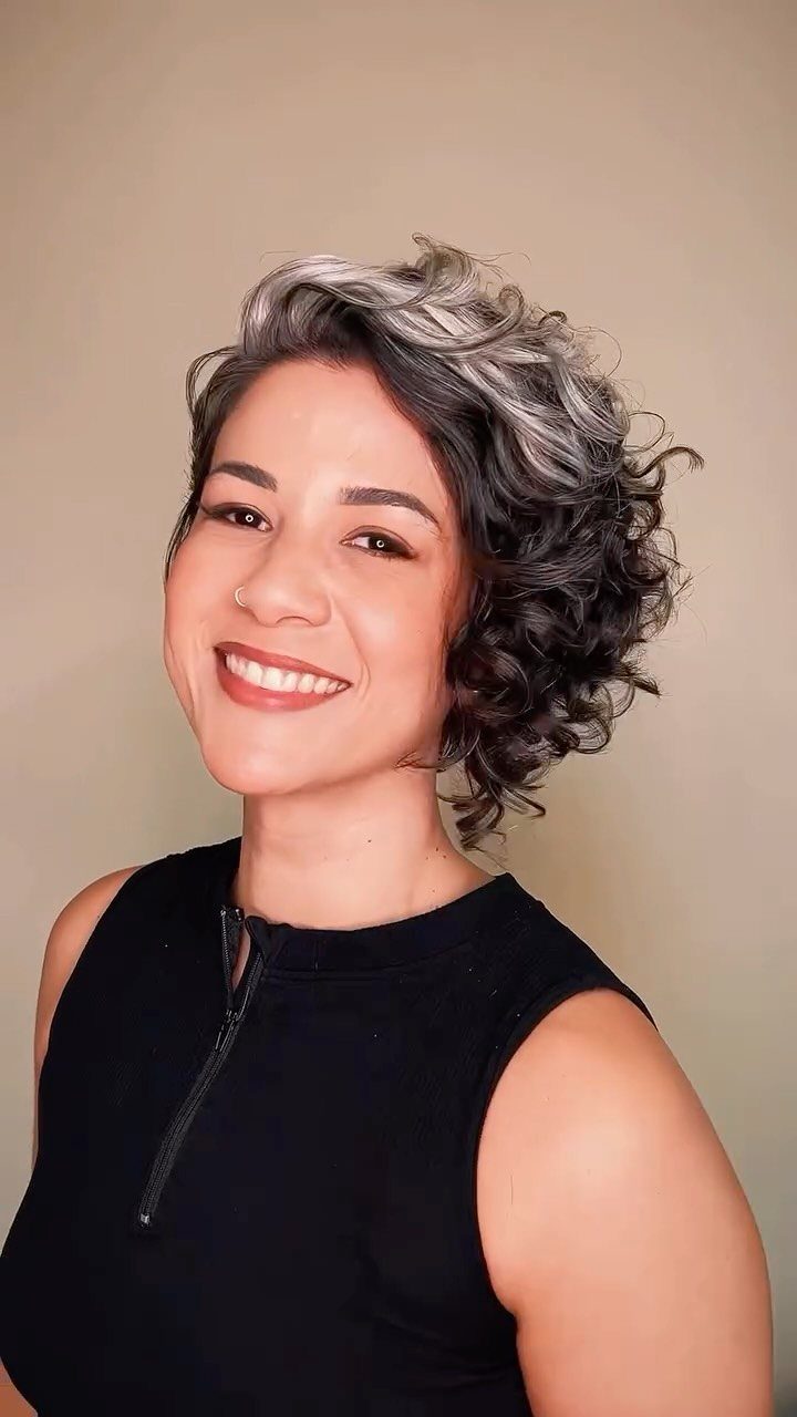 Woman with silver-highlighted asymmetrical curls in a short pixie cut