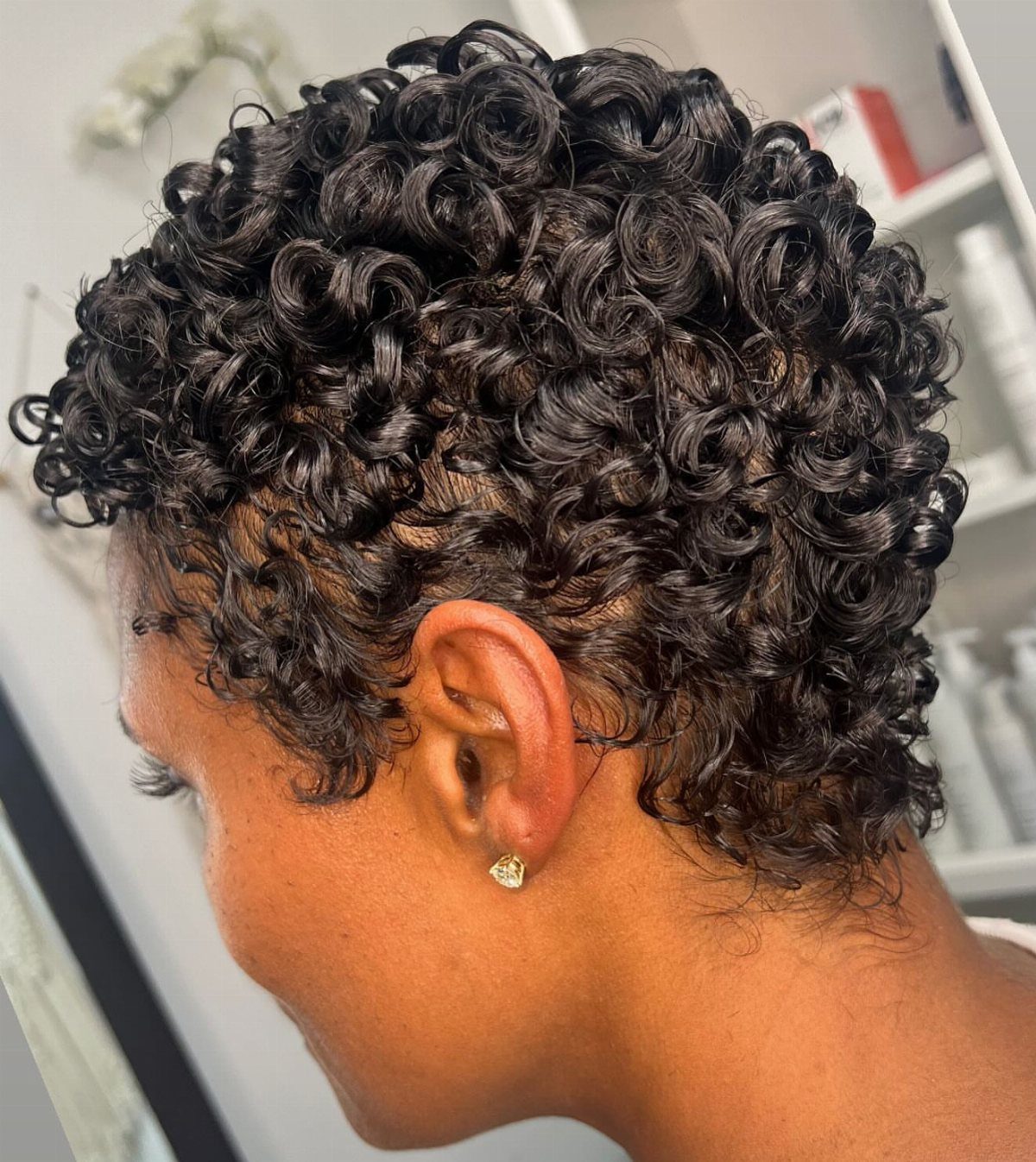 Short curly pixie cut with defined black curls and a closely cropped nape