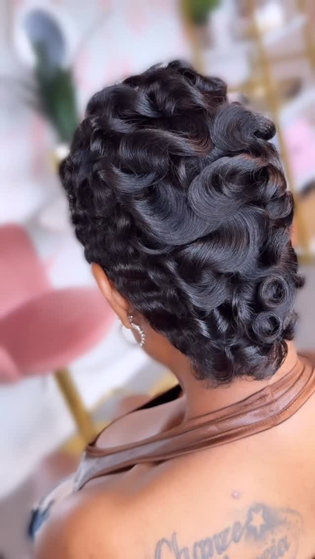 Short dark pixie cut styled with glossy curls and waves