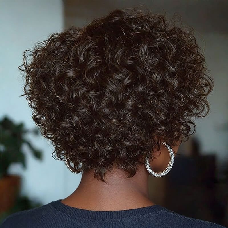 Short rounded dark curls cover the back of a person's head above a navy top