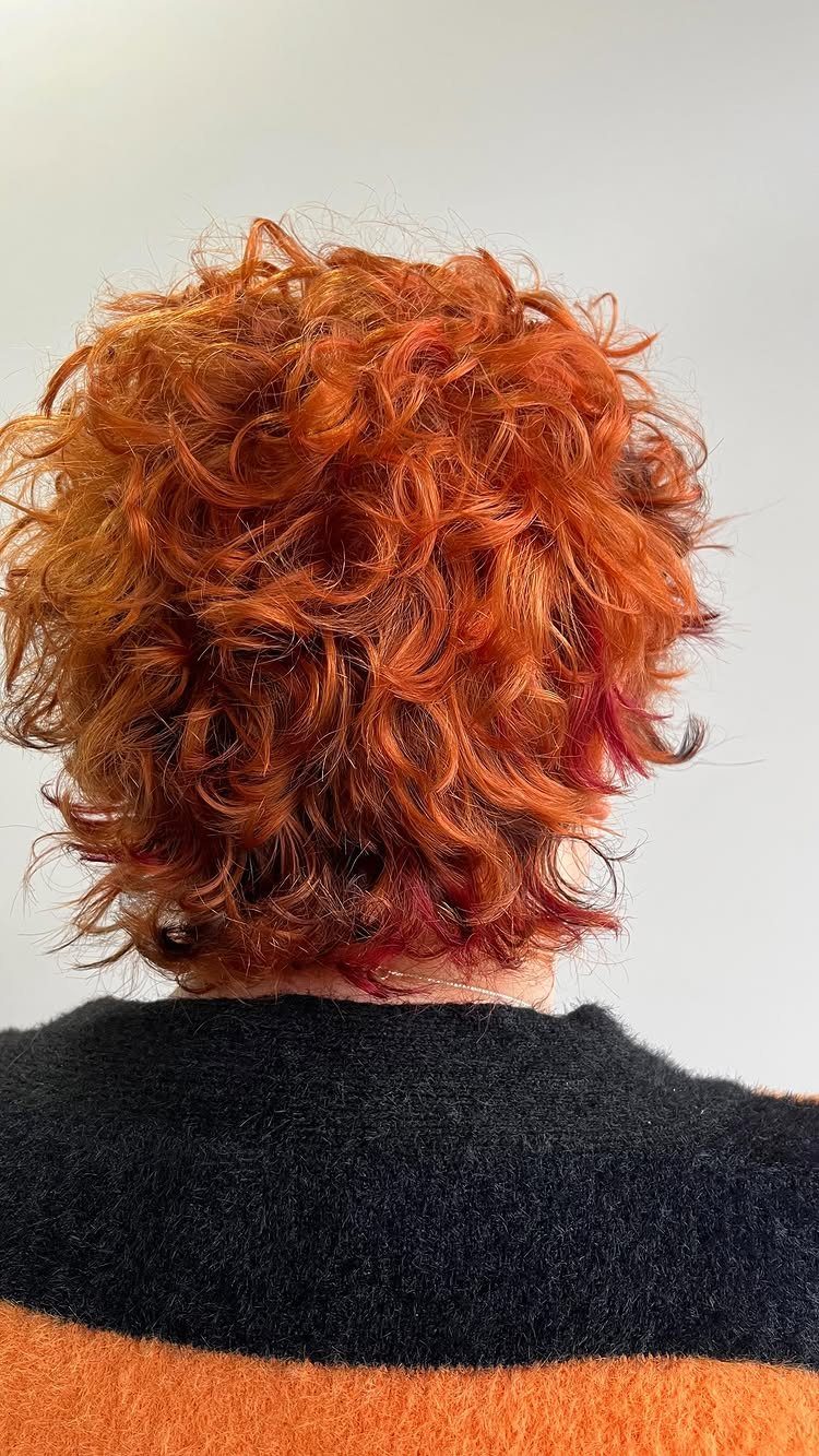 Short sun-kissed red curls with lighter highlights viewed from behind