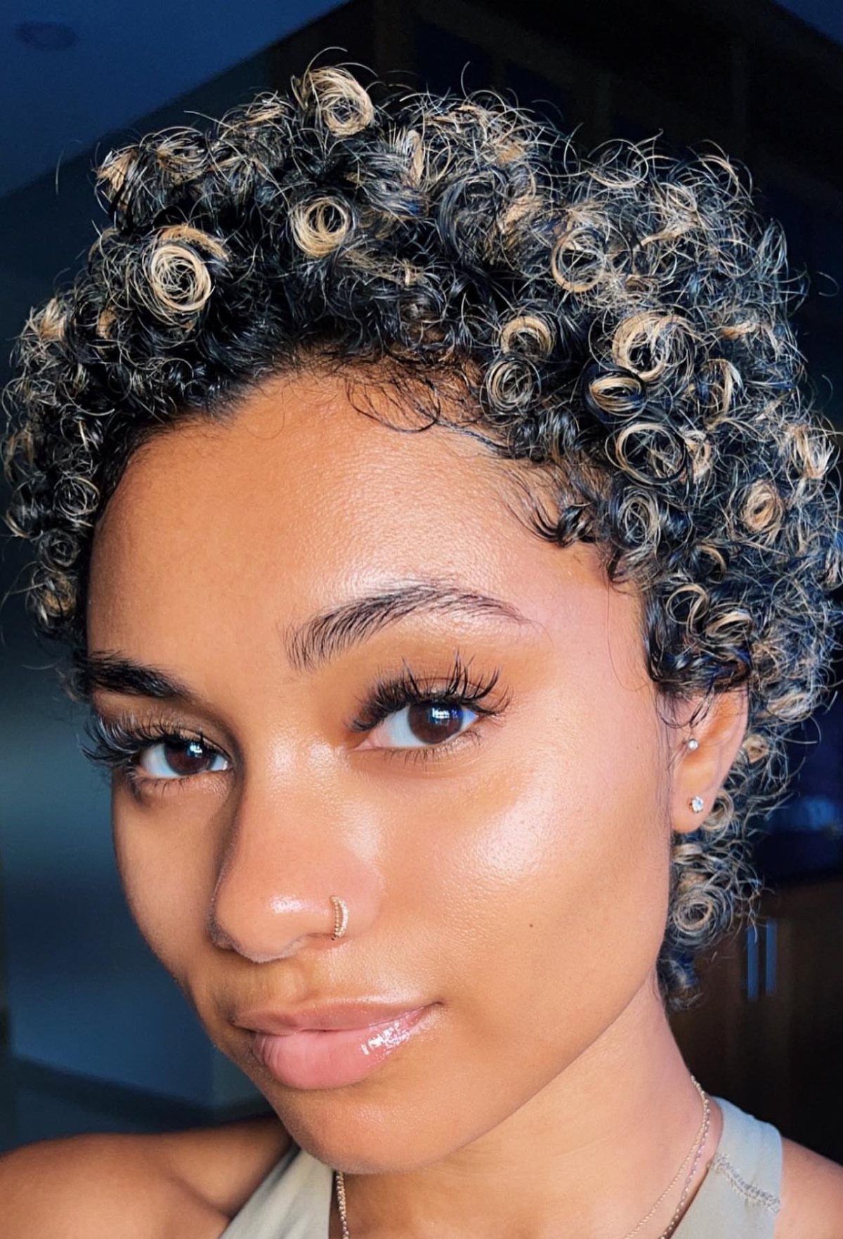 Woman with short dark curls and sunlit blonde highlights