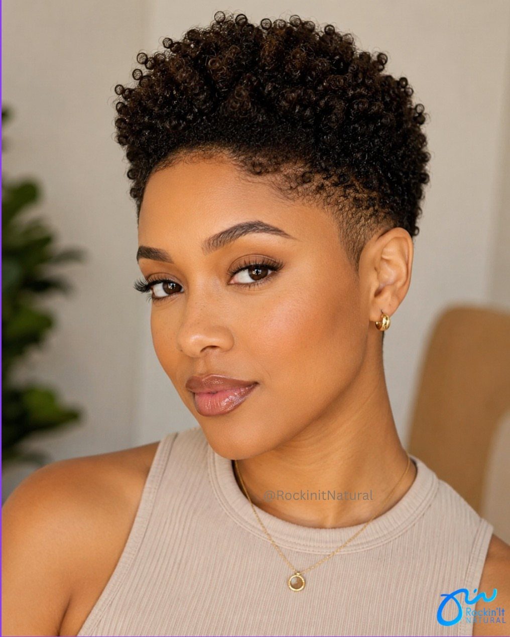 Woman with tightly curled pixie cut and closely tapered sides poses indoors