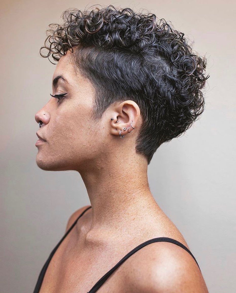 Short dark curls with a closely clipped undercut and textured volume on top