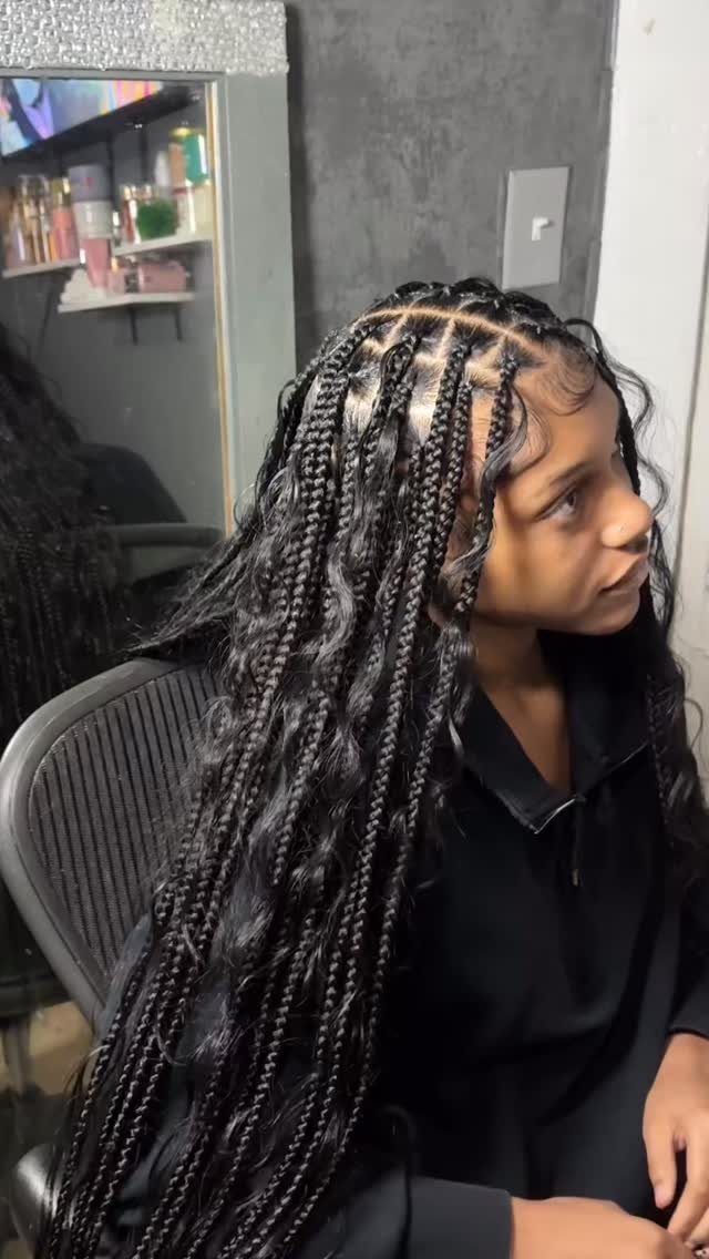 Woman showing long boho braids with loose curls in a salon chair
