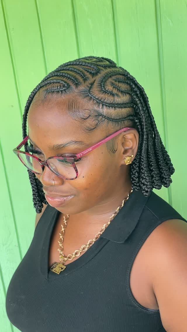 Woman wearing a short braided bob with curved cornrow patterns and pink glasses