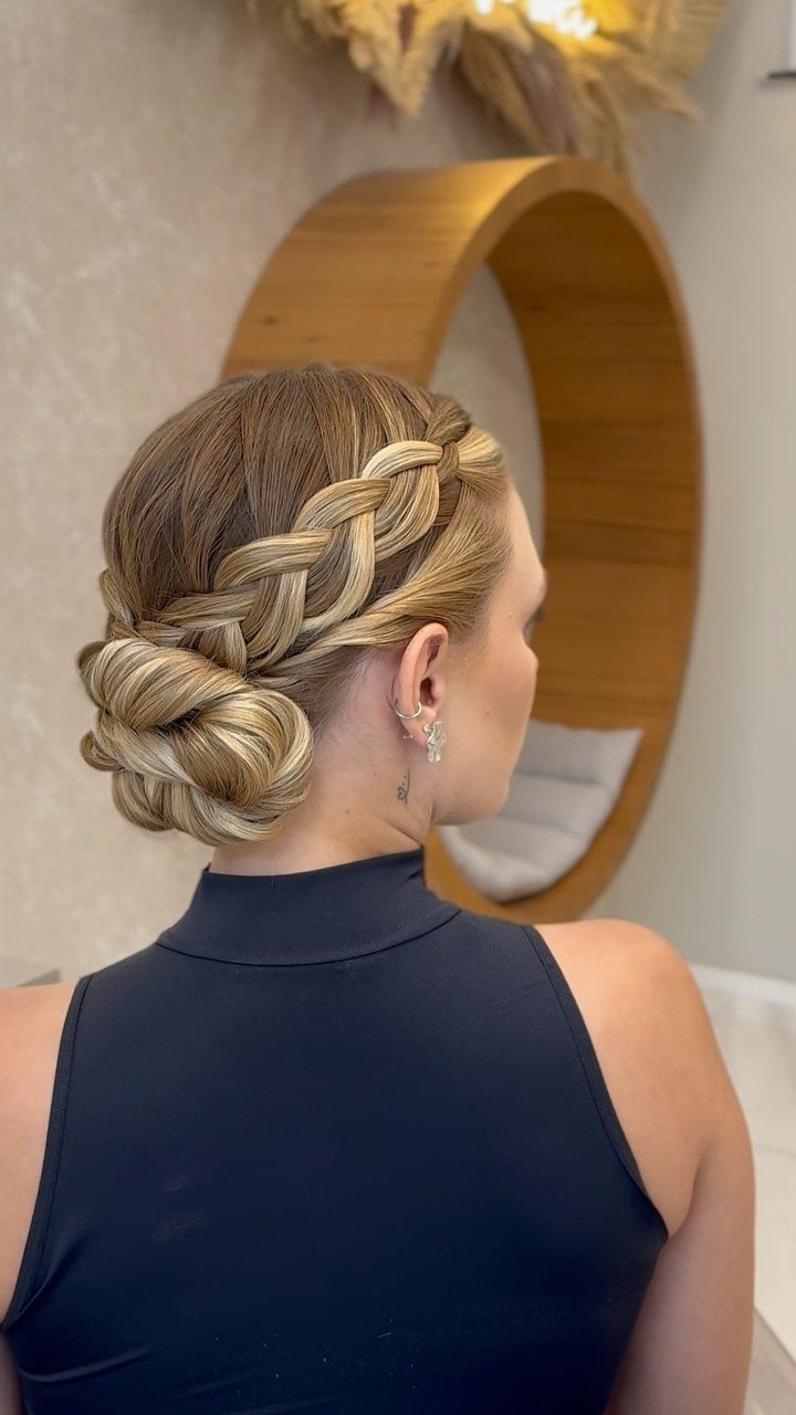 Woman showing a thick braided updo gathered into a low bun