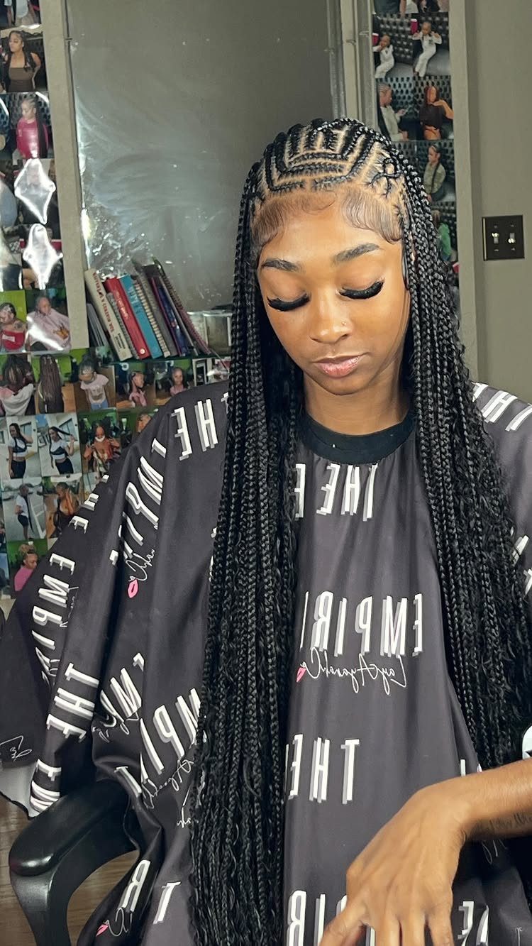 Woman displays long knotless braids with neat curved scalp parts in a salon