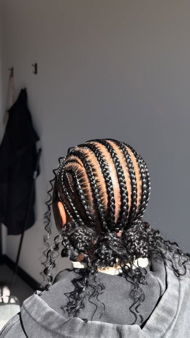 Cornrows gathered low with loose, voluminous curls at the ends