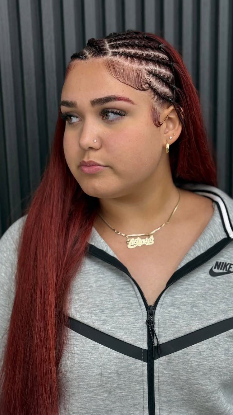 Woman displaying side cornrows woven into long dark red hair
