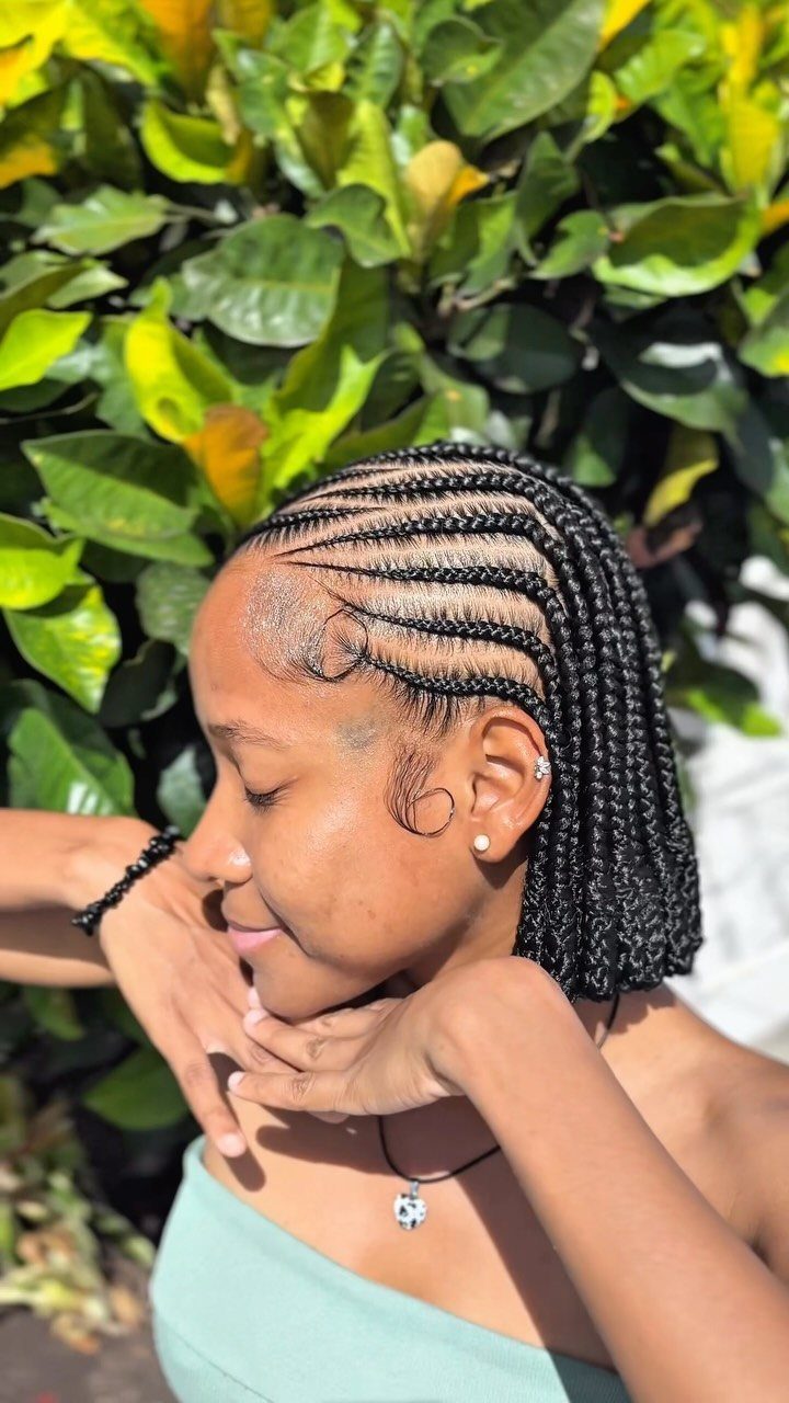 Woman wearing a short black feed-in braid bob swept back from her face