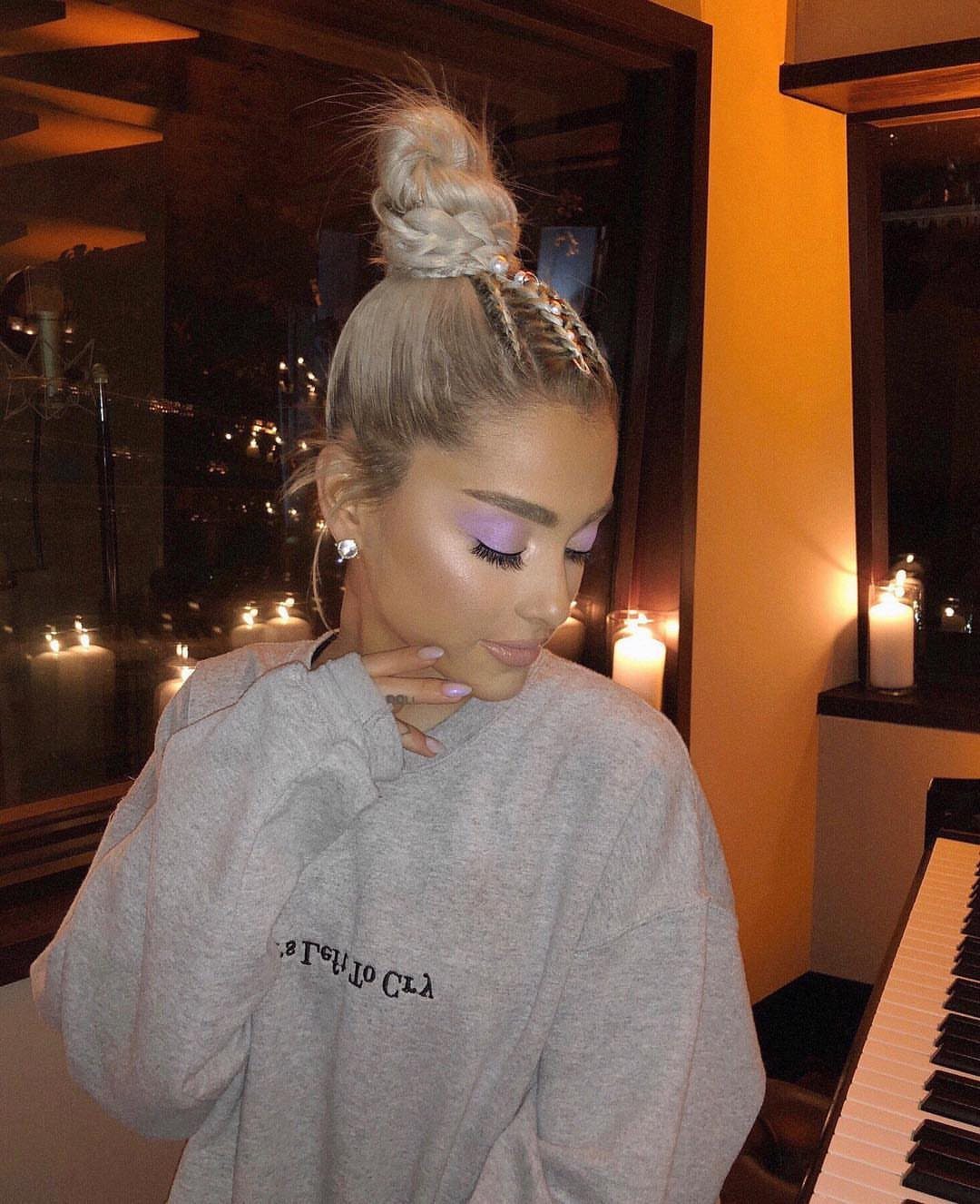 Woman wearing a braided blonde topknot in a warmly lit indoor room