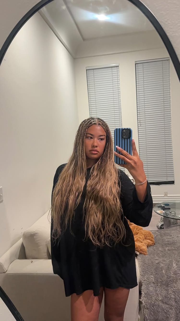 Woman displays long braids blended with loose curls in a bedroom mirror selfie