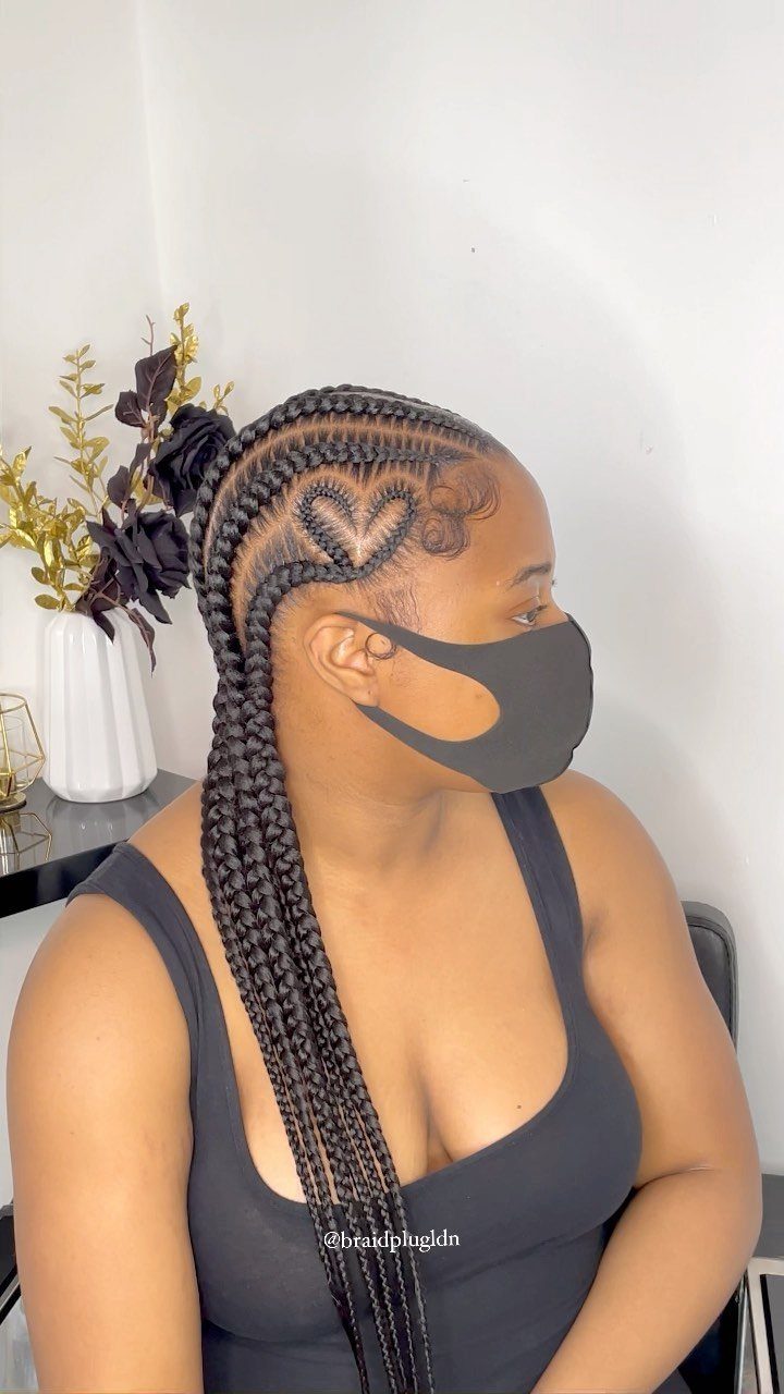 Woman with long braids featuring a heart-shaped cornrow pattern above her ear