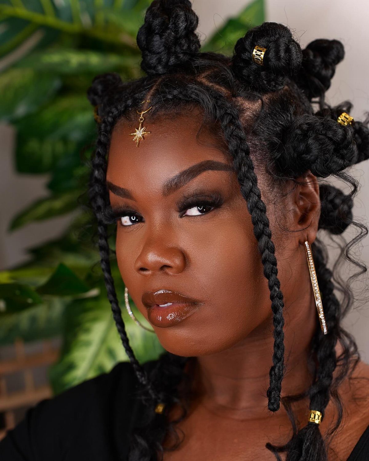 Woman wearing a crown of Bantu knots and long box braids with gold cuffs