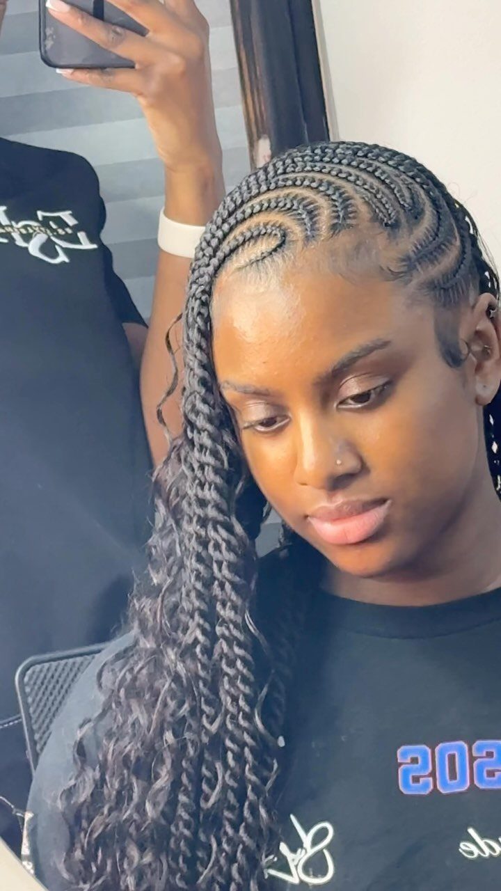 Swept cornrows merge into long black braids over one shoulder