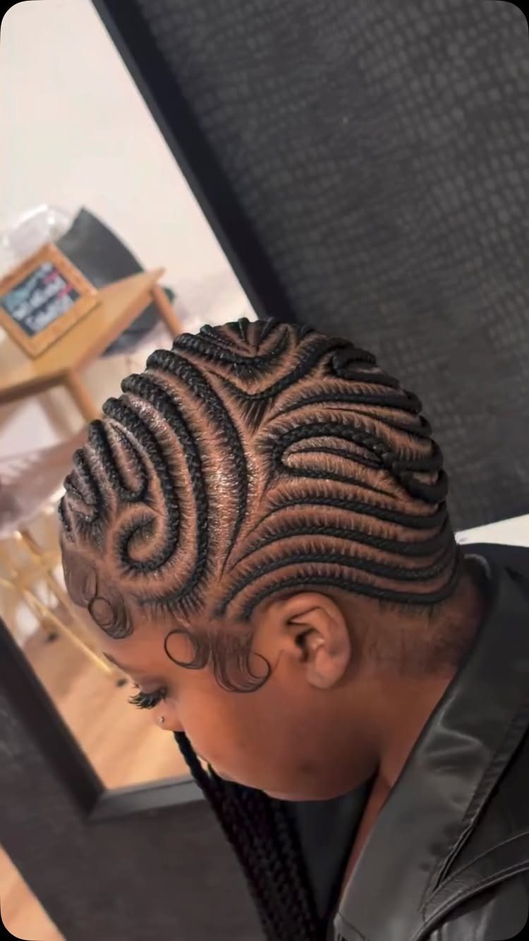 Curved cornrows form decorative swirls across the scalp