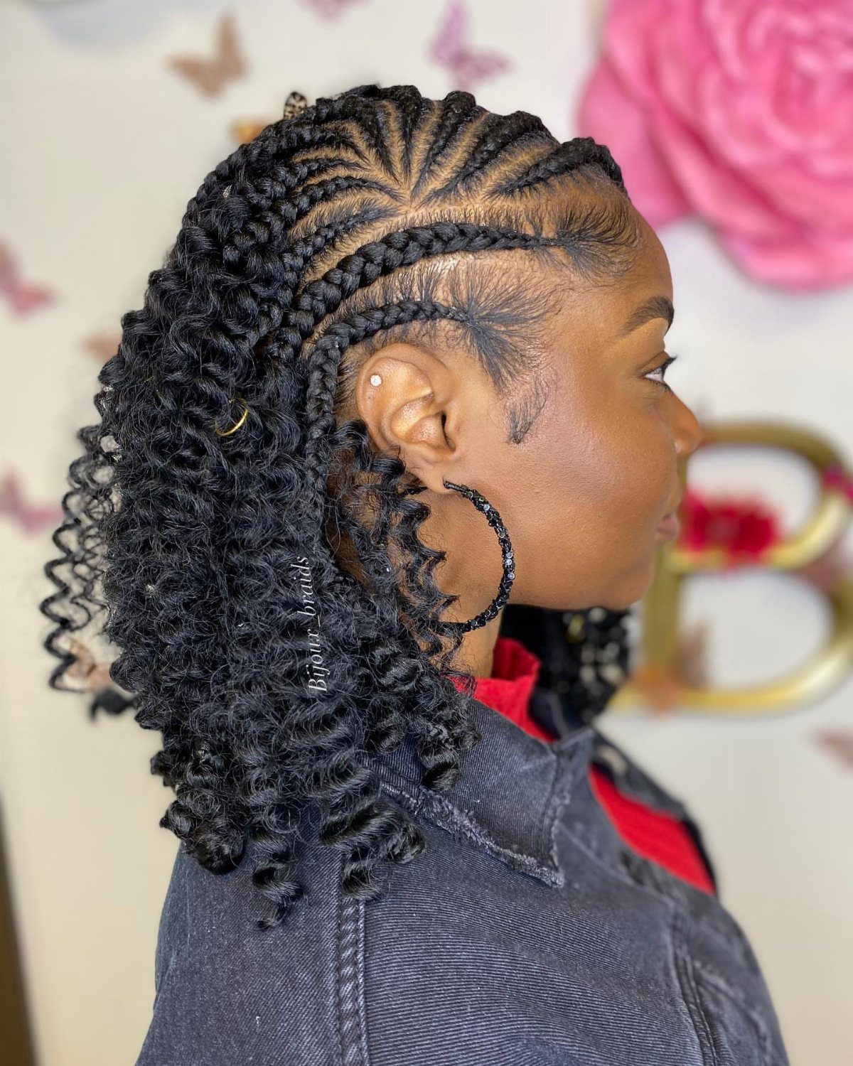 Side-swept black braids with curled ends frame a woman's profile.