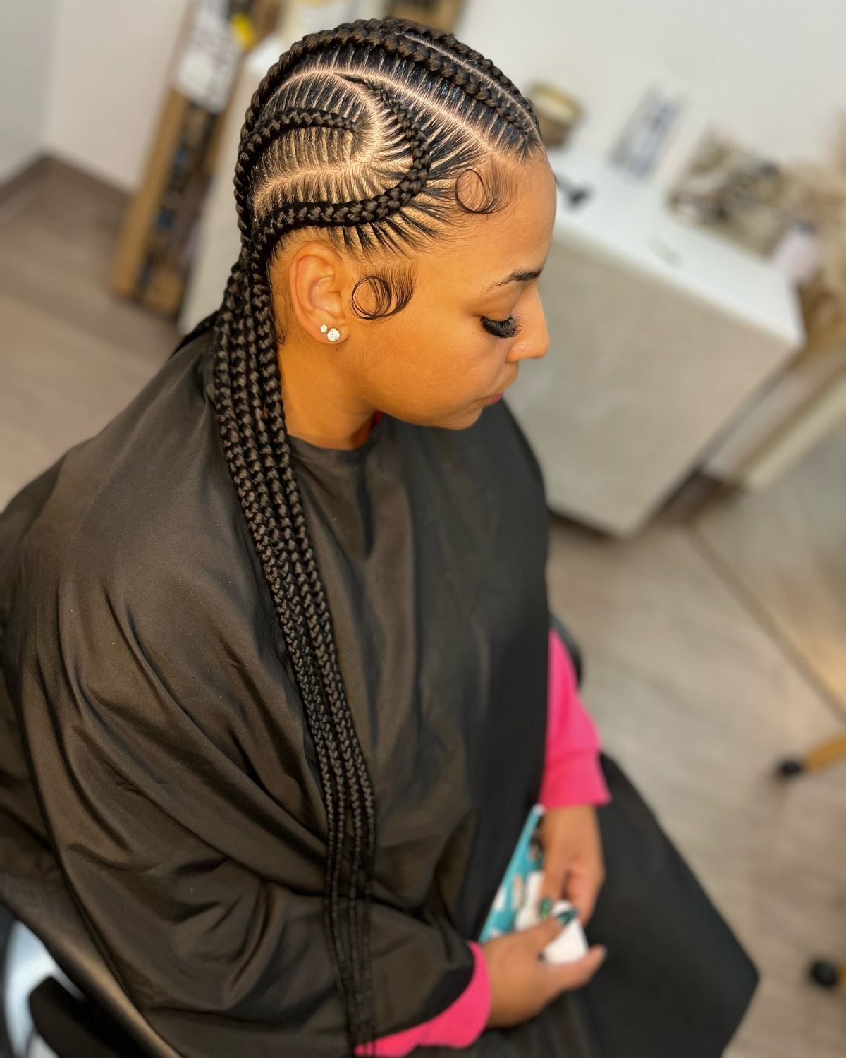 Side view showing long black braids in curved maze-like scalp patterns