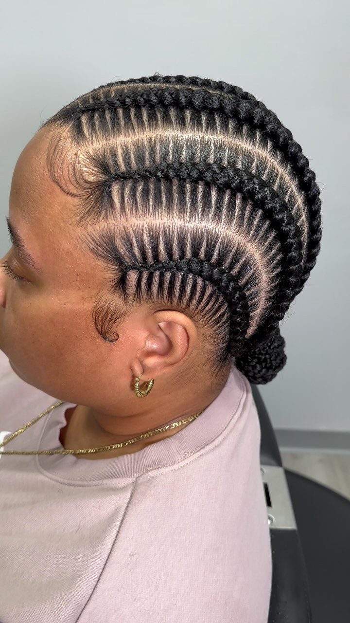 Straight-back cornrows run from the hairline into a low bun