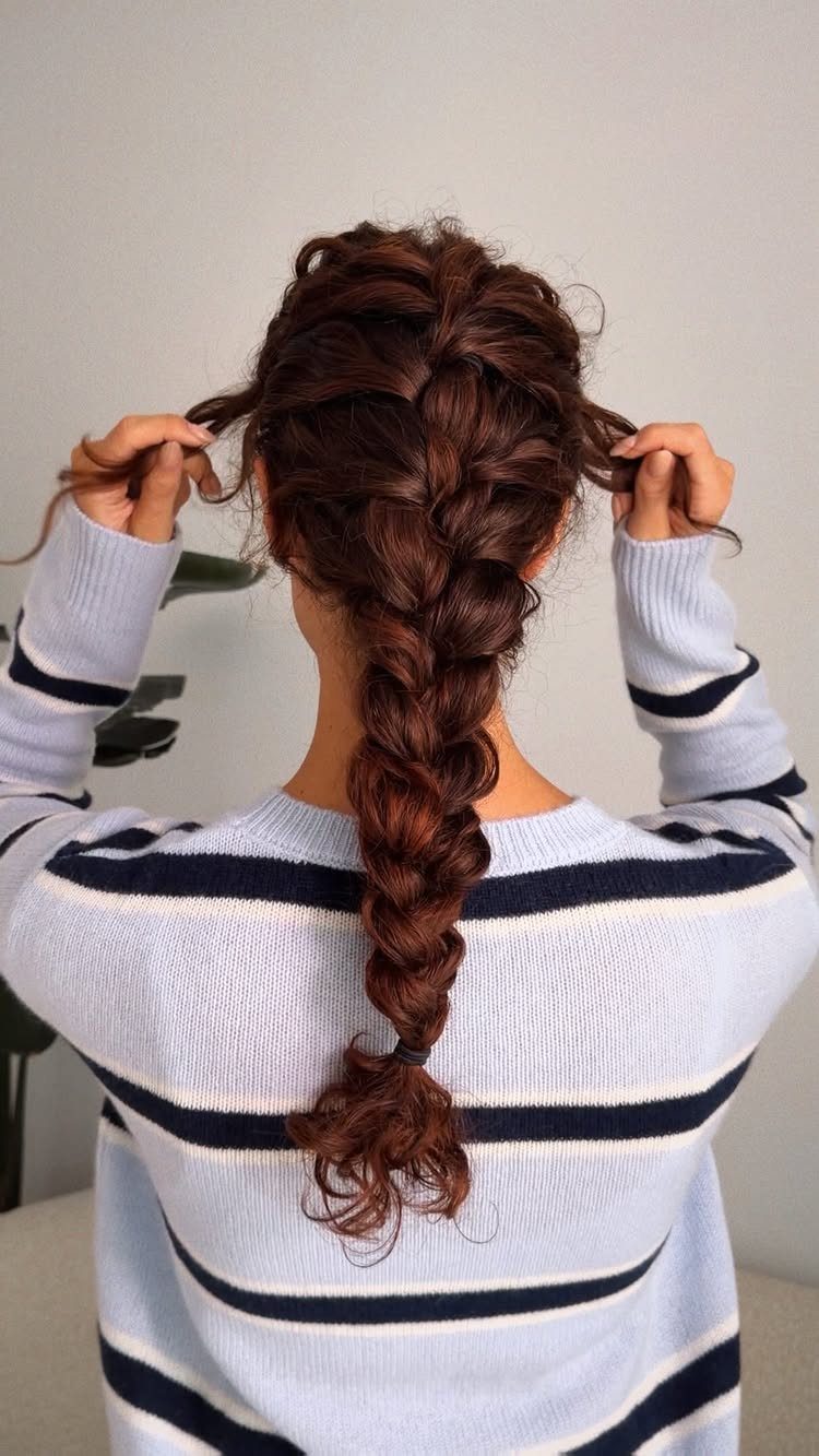Curly brown hair woven into a long textured French braid from behind