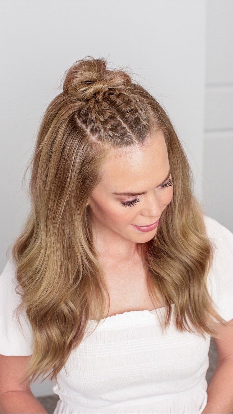 Woman showing a French braid gathered into a small top bun with loose waves