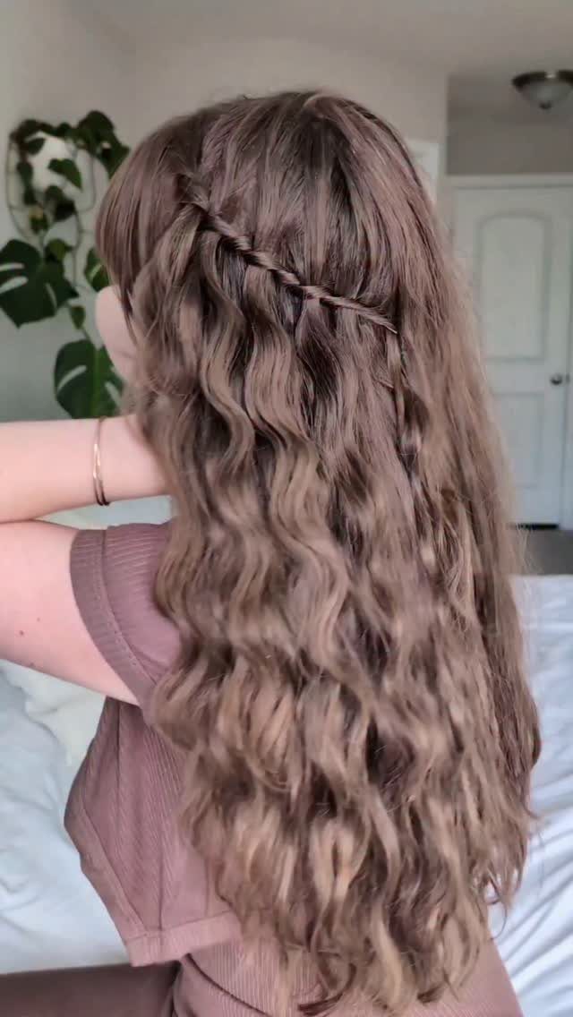 Long wavy brown hair styled in a cascading waterfall braid