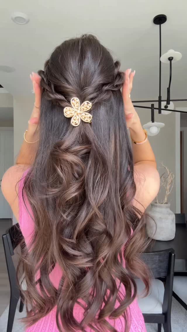 Half-up French braids secured with a gold flower clip over long loose curls