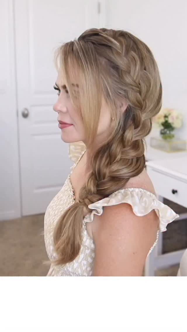 Blonde side French braid draped over one shoulder with loose face-framing strands
