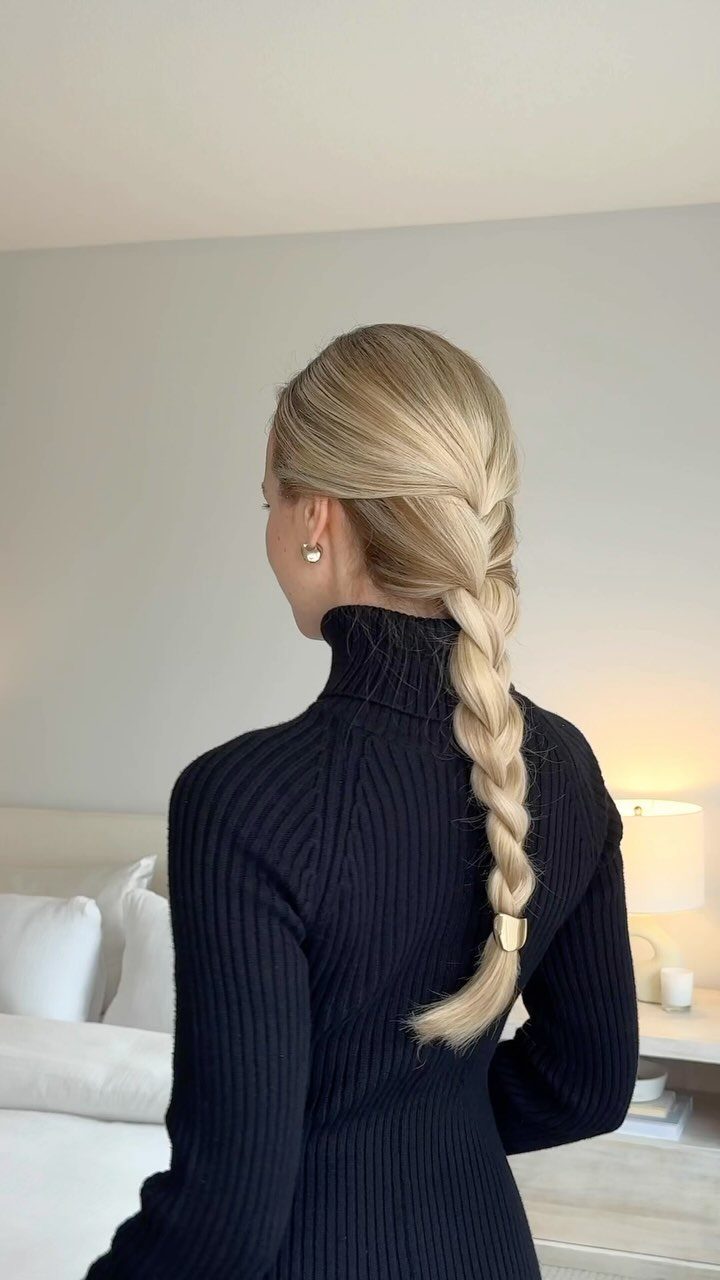 Blonde French braid falling down the back of a black turtleneck