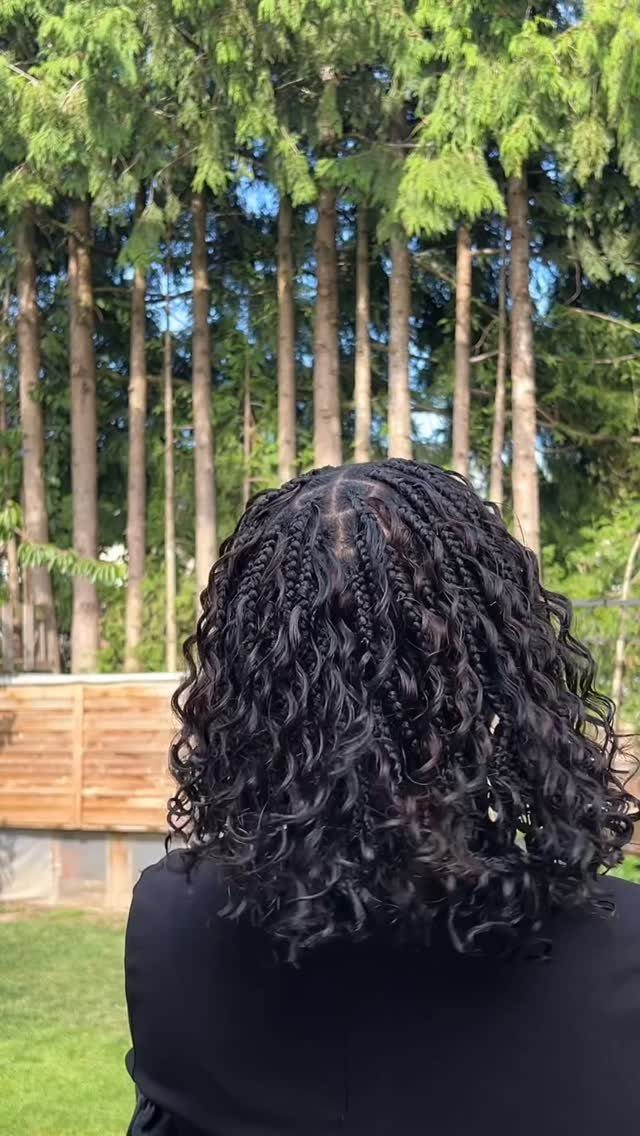 Dark boho braids with loose curly strands shown from behind outdoors