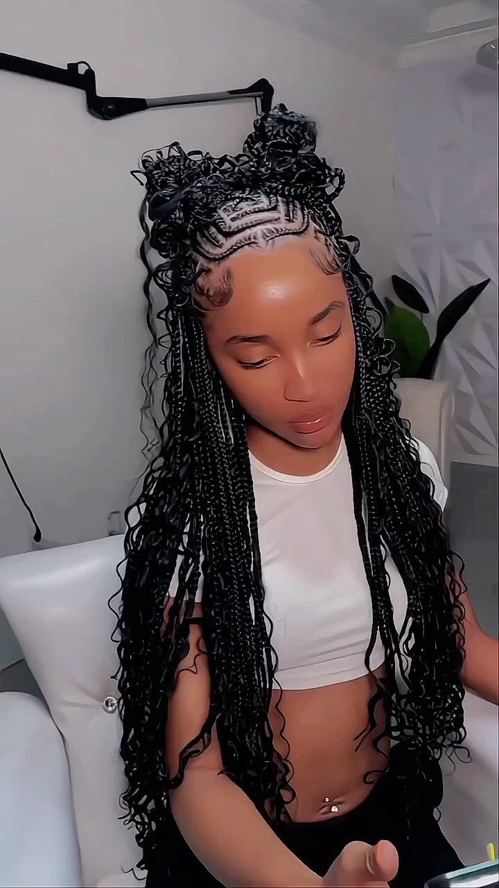 Woman with long black individual braids and close scalp rows, wearing a white sleeveless top