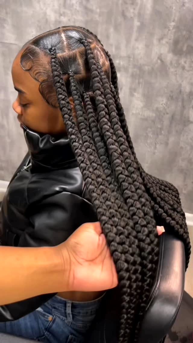 Large thick black braids extending down a person's back, held by a hand
