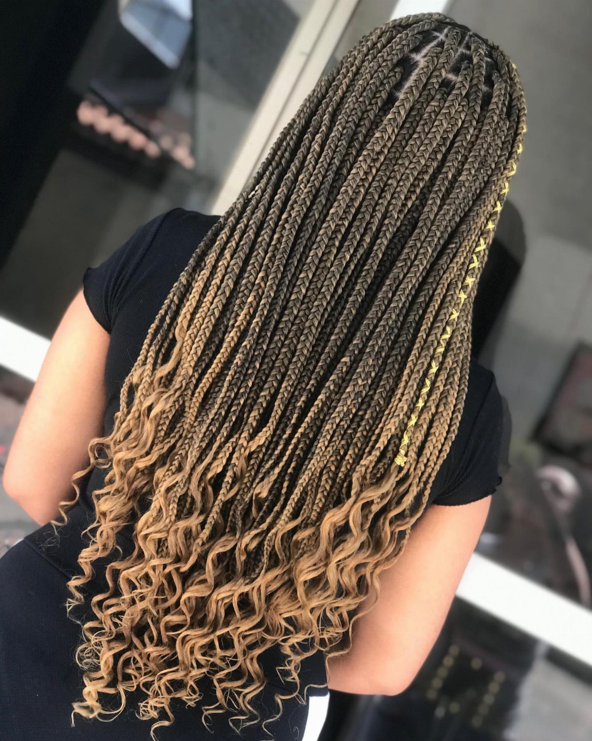 Long dark box braids fade to light brown curly ends on a person