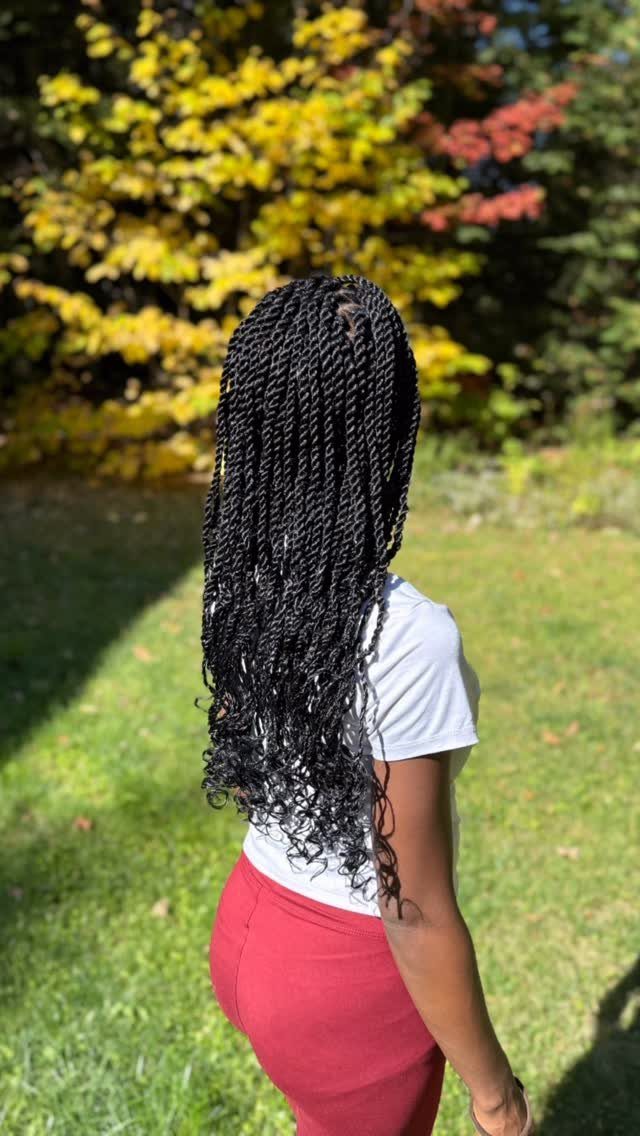 Long black Senegalese twists fall down the back of a person outdoors