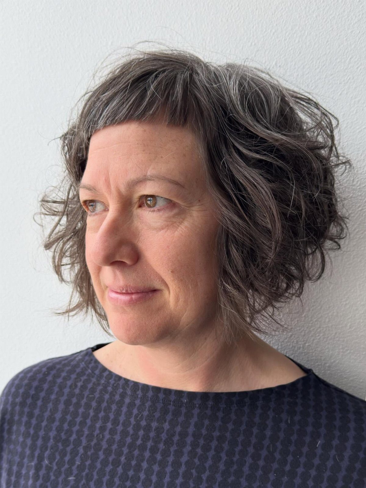 Woman showing a short curly bob with a very short fringe