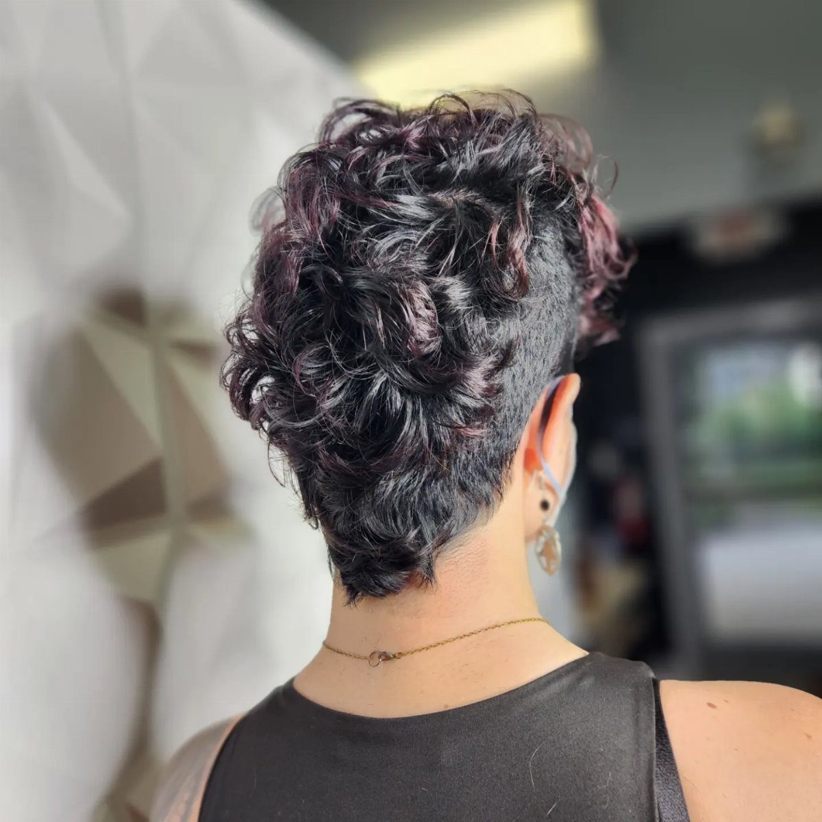 Curly mohawk with voluminous top, cropped sides, and tapered nape