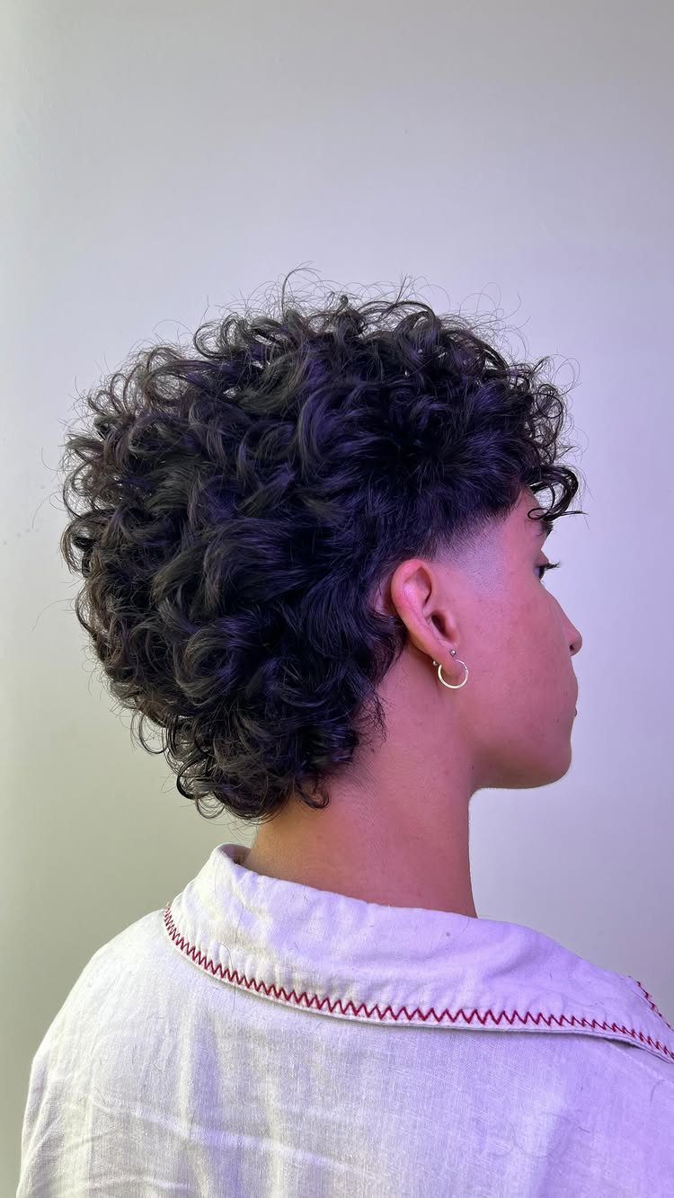 Curly mullet with short sides and longer curls at the back