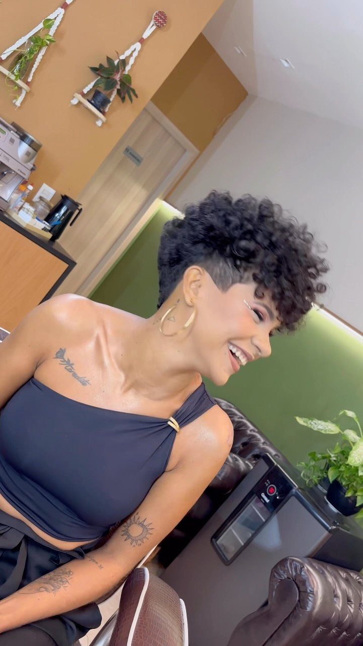 Woman showing a curly pompadour with voluminous curls above closely cropped sides