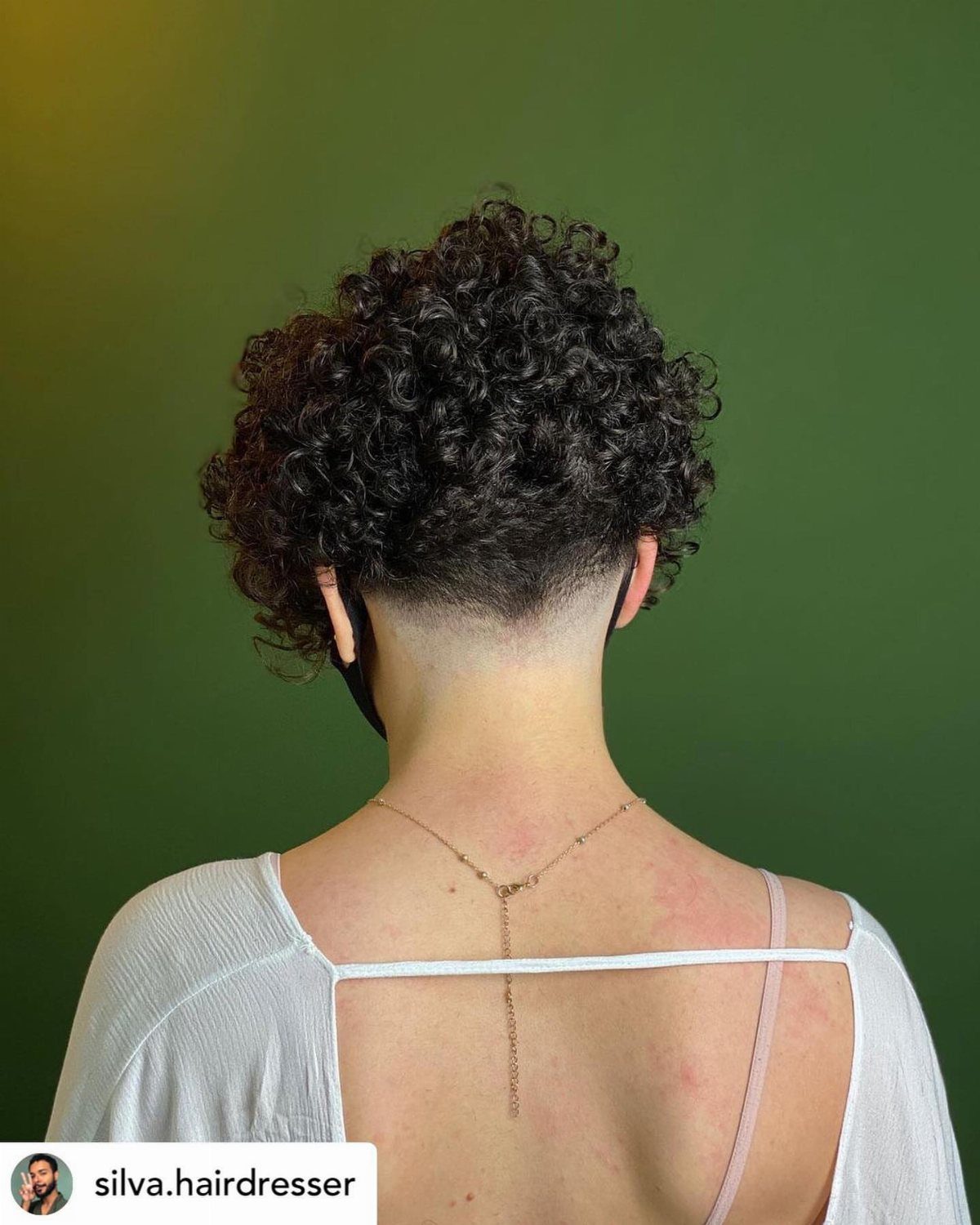 Curly undercut with voluminous dark curls and shaved sides