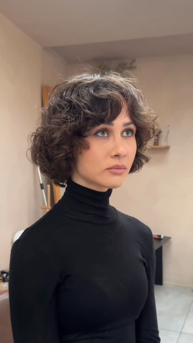 Person showing short dark curls with textured fringe across the forehead