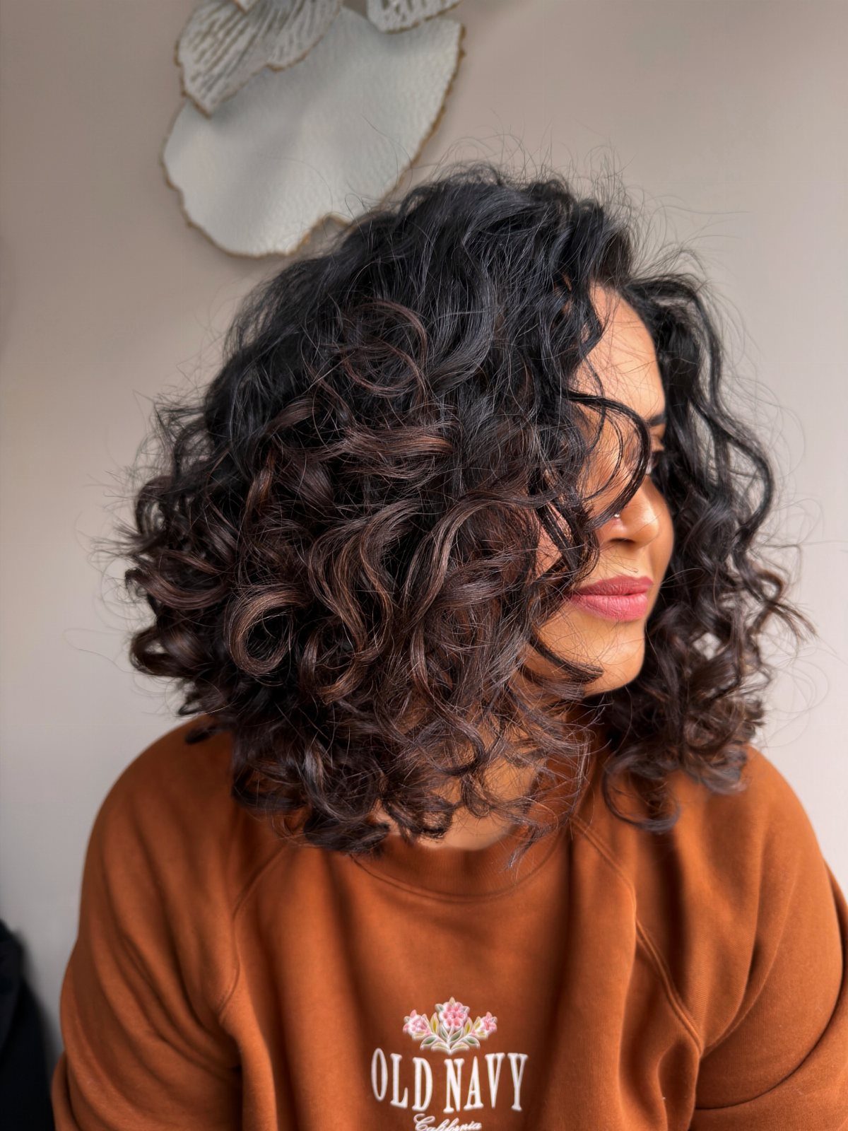 Woman showing a layered shoulder-length curly bob with voluminous dark ringlets