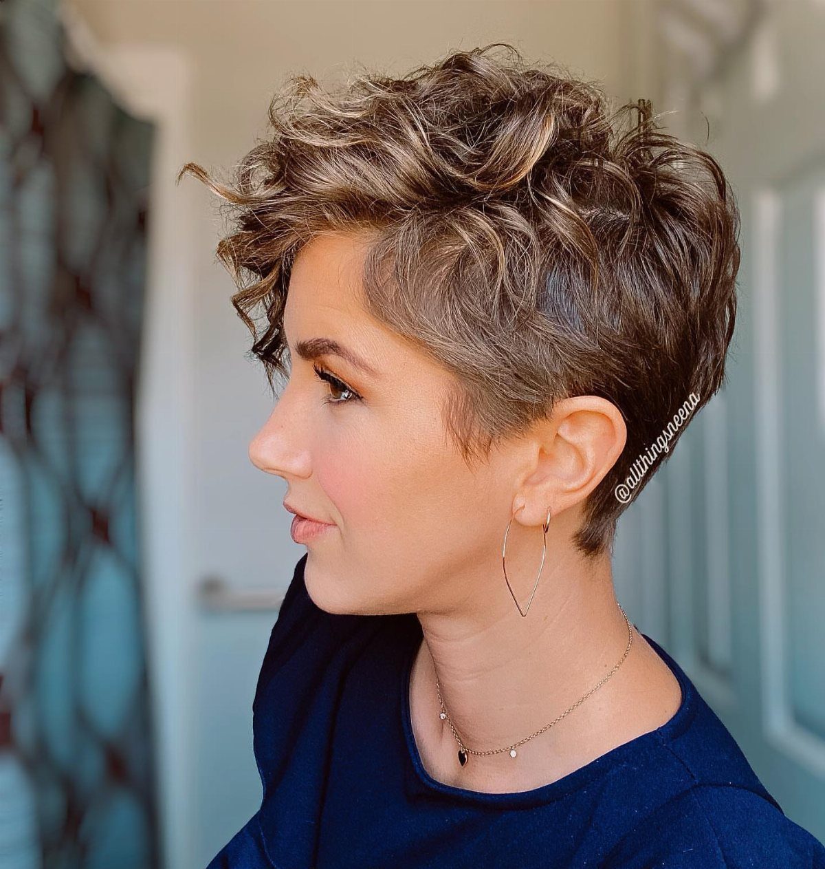 Woman showing a short wavy pixie cut with layered brown hair and tapered sides
