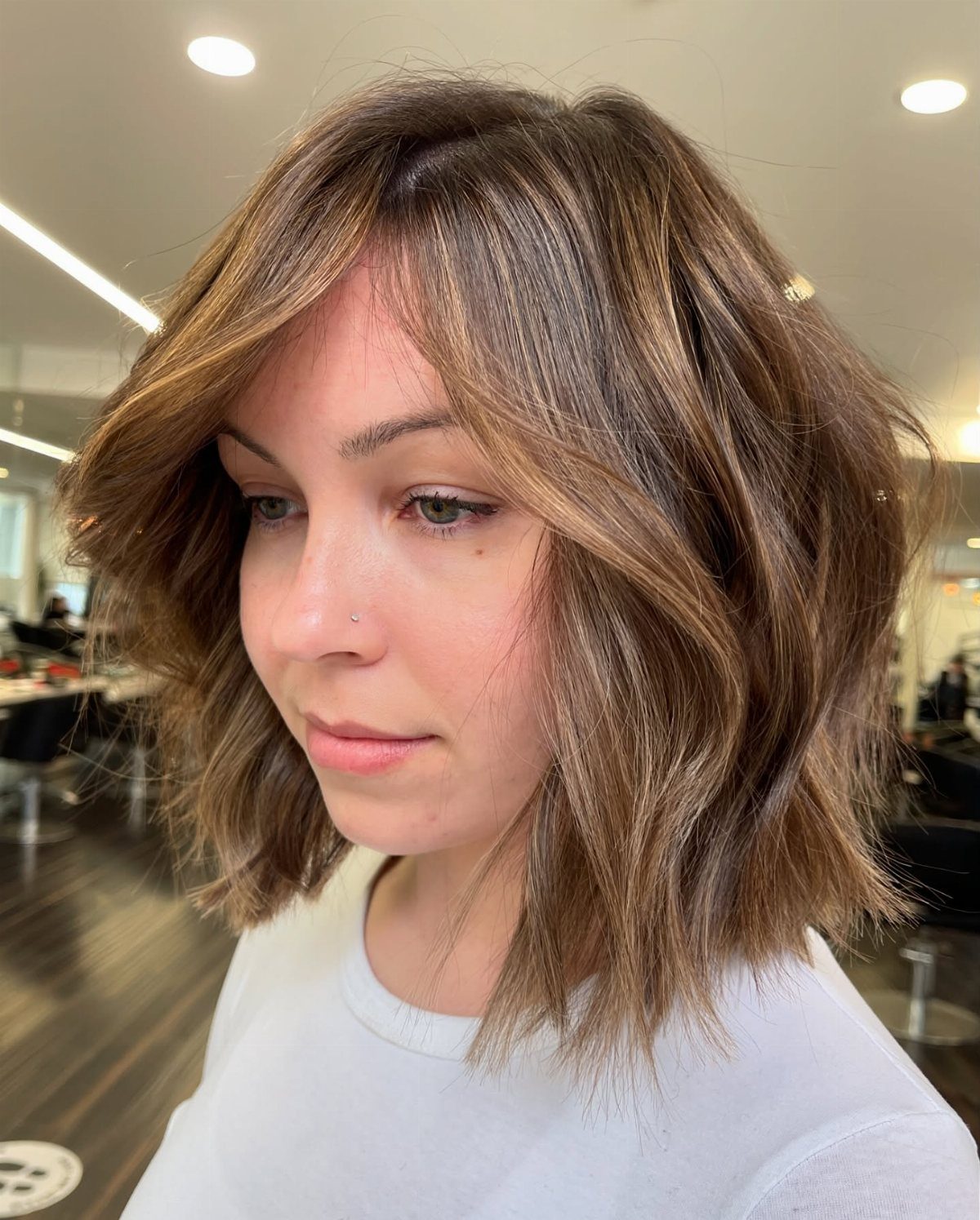 Woman wearing a wavy highlighted bob with piecey layers in a salon