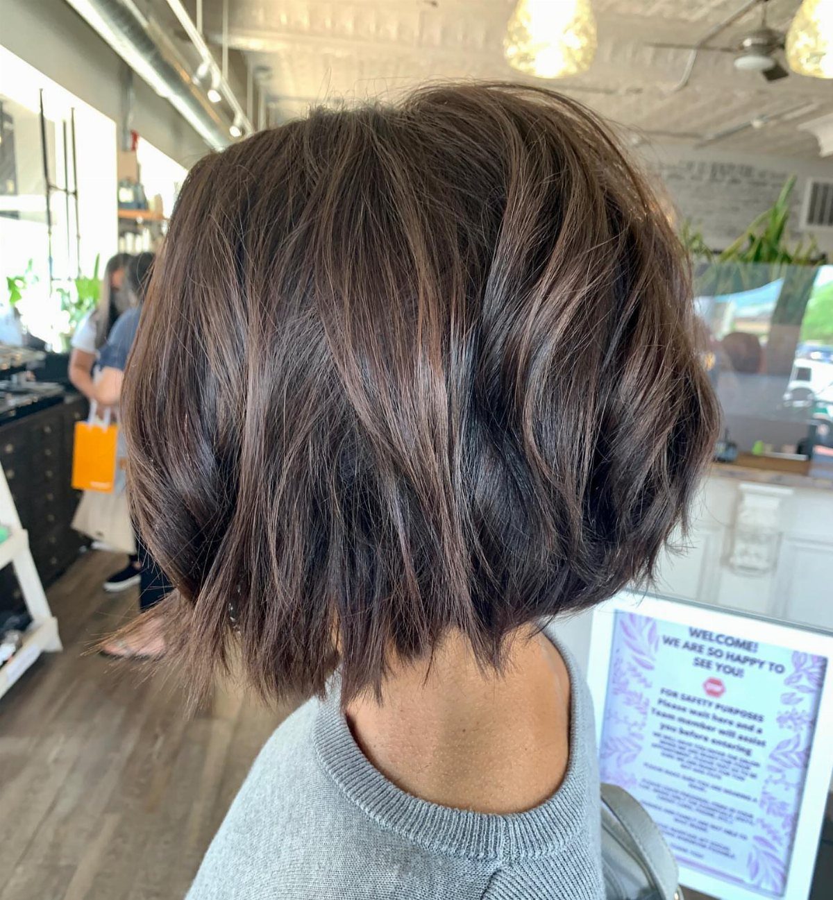 Dark tousled angled bob haircut shown from behind in a bright salon