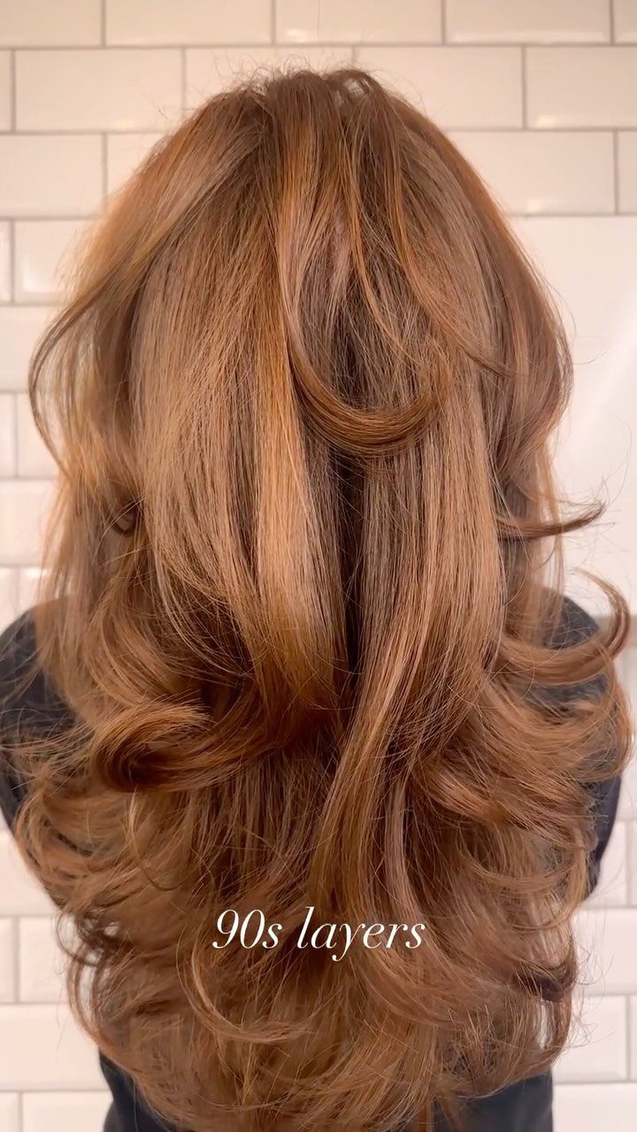 Long auburn hair styled in voluminous cascading layers with curled ends