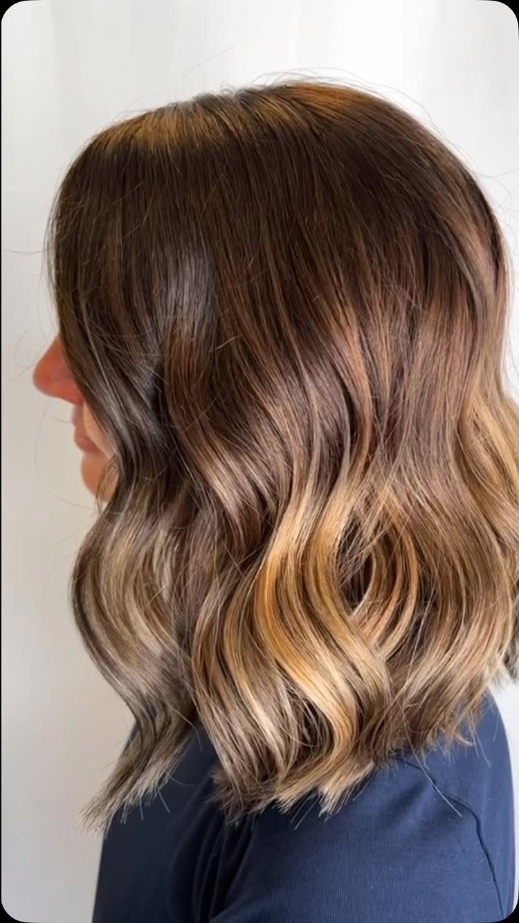 Shoulder-length highlighted brown hair styled in loose, textured waves