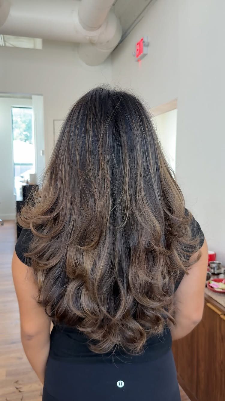 Long dark wavy hair with blended layers and curled ends seen from behind