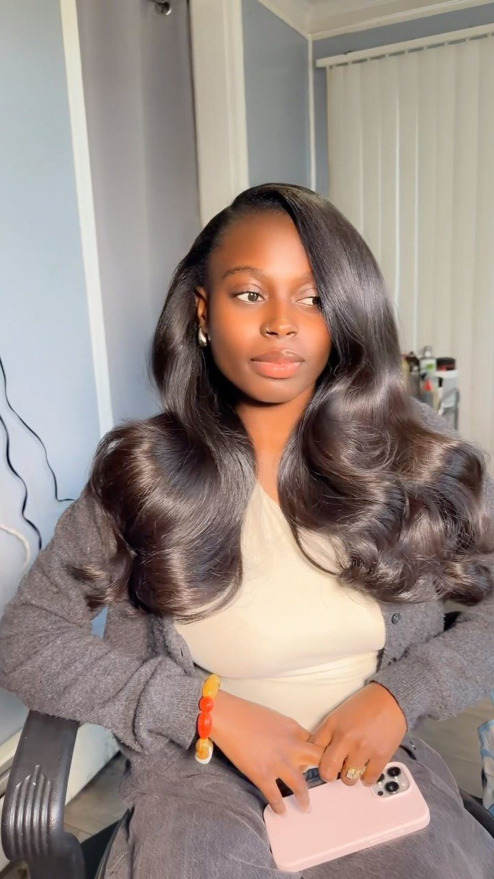 Woman with long, layered dark hair styled in voluminous waves