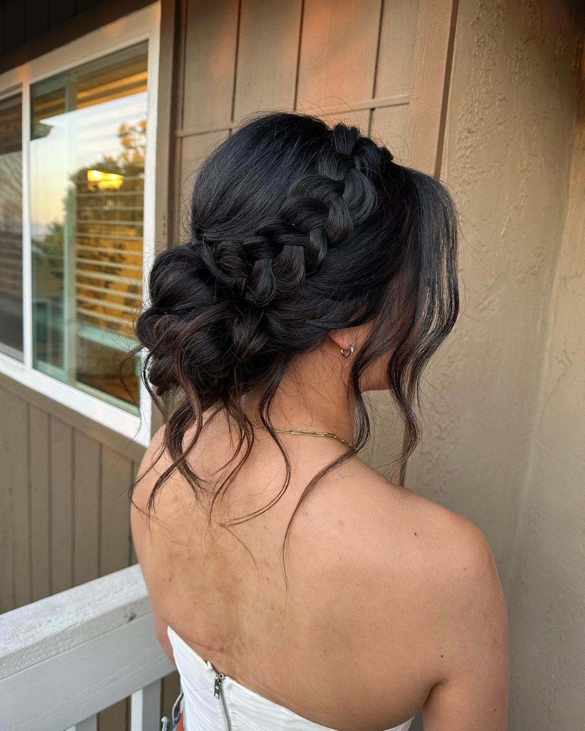 Woman showing dark curly hair in a braided updo with loose tendrils